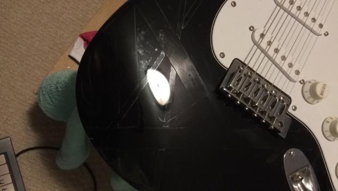 How can I safely remove tape residue from my guitar?