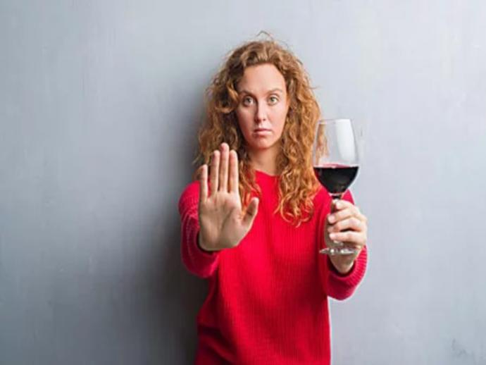 What type of drink is in the glass that this woman is holding and would you drink it?