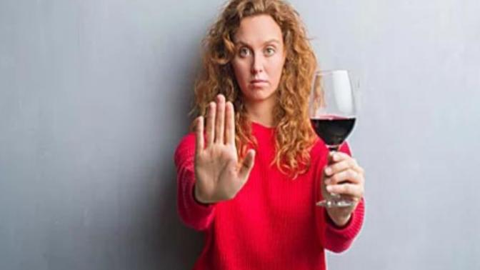 What type of drink is in the glass that this woman is holding and would you drink it?