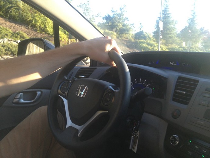 Why do men drive with one hand at the top of the steering wheel?