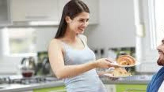 Why do many women frown at serving their man food at the table?