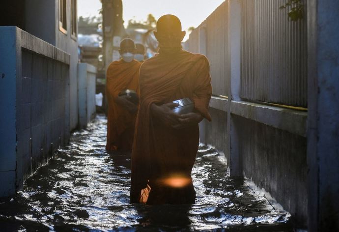 Monks walk to receive alms on a flooded street in Koh Kret in Nonthaburi, in the outskirts of Bangkok, Thailand.