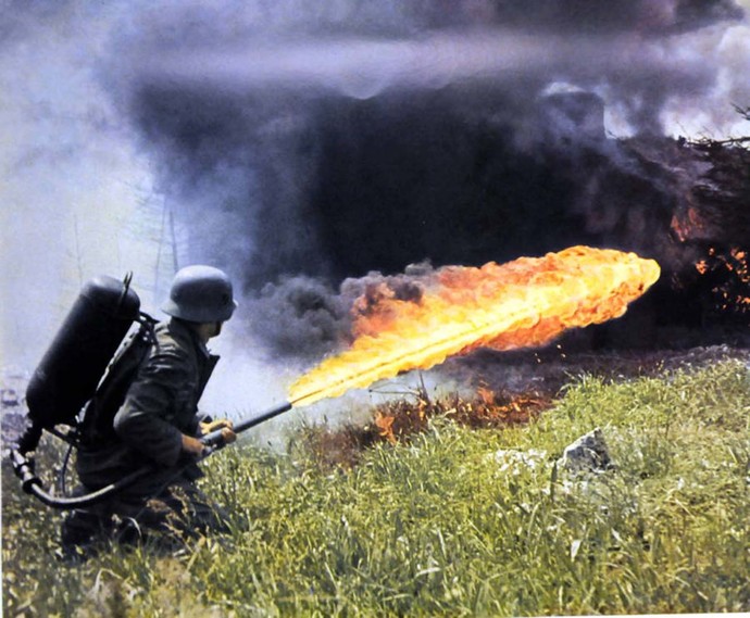 A German solider fires a backpack flamethrower across a field of tall grass in the Soviet Union, 1941-1942.
