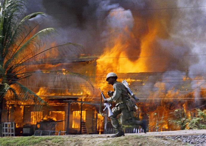 A US soldier runs past a burning building in Saigon, during the Tet Offensive. Vietnam, 1968.