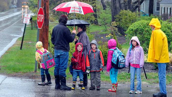 How should kids WAIT for the SCHOOL BUS when it's RAINING?