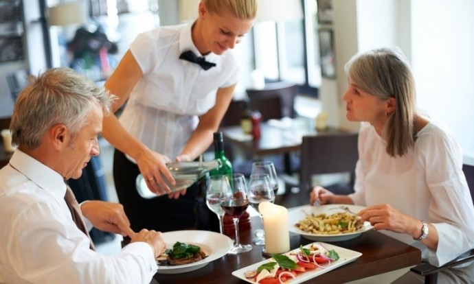 Why do waiters in the US have to rely on tips to earn a good salary?