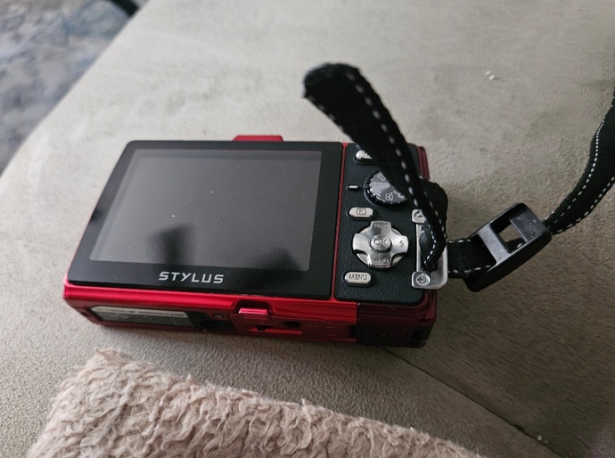 How do I properly attach this wrist strap to my handheld camera?