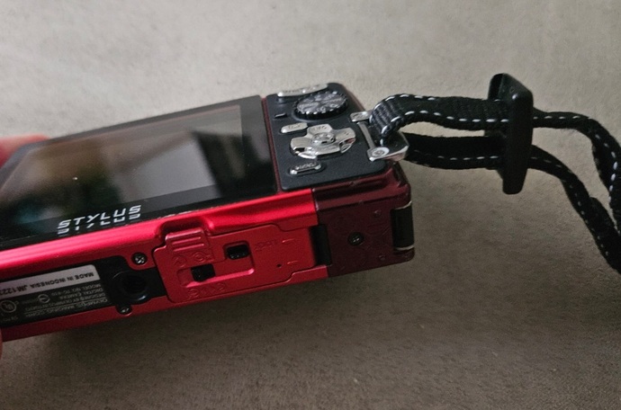How do I properly attach this wrist strap to my handheld camera?