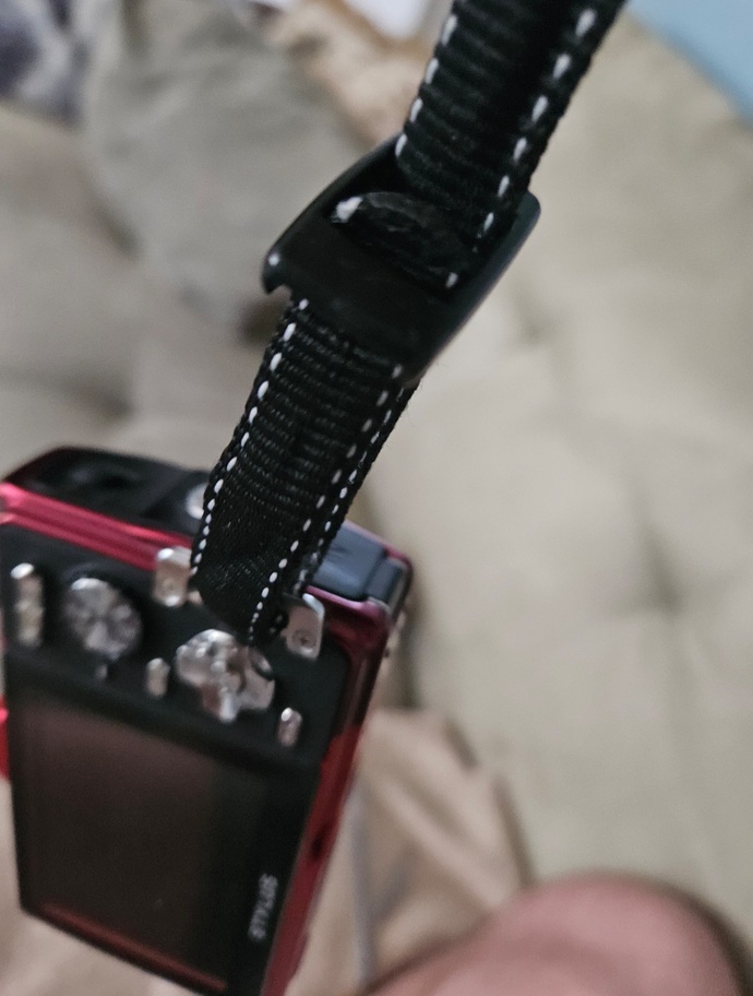 How do I properly attach this wrist strap to my handheld camera?