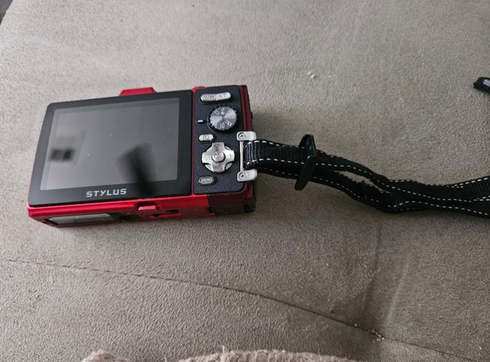 How do I properly attach this wrist strap to my handheld camera?