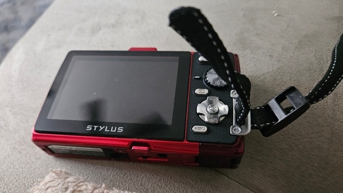 How do I properly attach this wrist strap to my handheld camera?